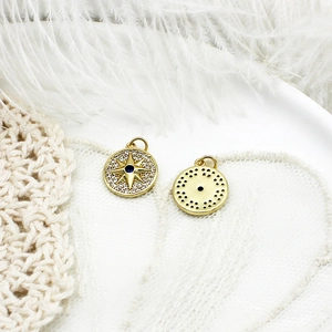 Detailed macro view of gold-plated starburst compass charms with zircon and blue gemstone