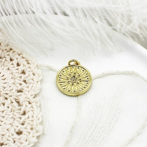 Macro detail of 18K gold plated sunburst compass pendant with micro zircon inlay