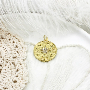 Detailed macro shot of an 18K gold plated celestial coin pendant with zodiac symbols