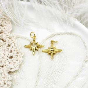 Macro shot of 18K gold plated star pendants with sparkling cubic zirconia on lace background
