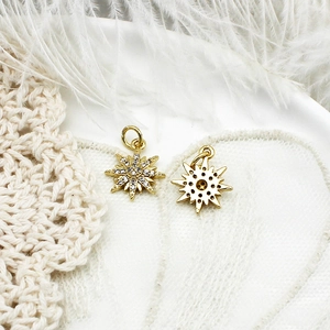 Close-up of 18K gold star pendants with micro-pave zircon on elegant lace and feather background