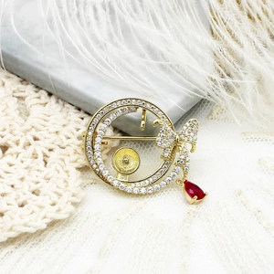 Golden butterfly brooch with sparkling crystals and a red teardrop pendant on lace