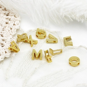 Makro-Detail von goldenen 3D-Alphabet-Perlen für DIY-Schmuck mit Querloch-Design
