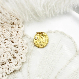 Macro detail of oval gold pendant with religious relief carving and single zircon stone
