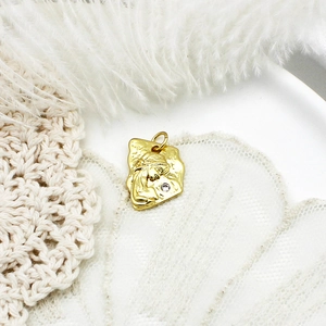 Close-up of a vintage gold-toned coin pendant featuring female portrait and zircon