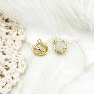 Macro shot of gold DIY pendants with round white cat eye stones for jewelry making