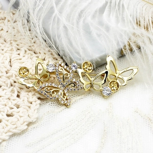 Broche papillon dorée exquise avec zircons brillants sur fond de plumes blanches douces