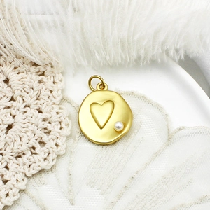 Golden heart pendant with small pearl on white feather and beige lace background