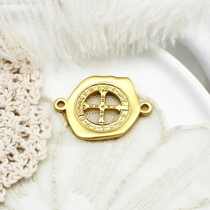 Macro shot of gold St. Benedict medal pendant with holy cross engraving on lace background