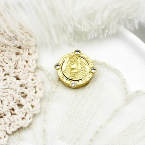 Detail of round gold pendant with classical portrait relief and four clear crystals