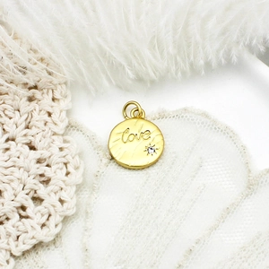 Close-up of golden heart pendant with Love engraving and zircon on lace and feather