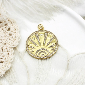 Macro shot of gold boho sunburst pendant with white zircon inlays and celestial symbols
