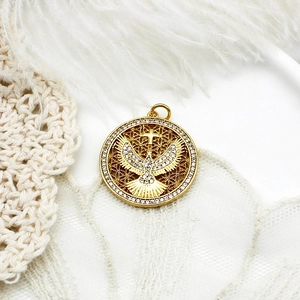 Macro shot of gold-plated dove pendant with zircon pavé and hollow pattern