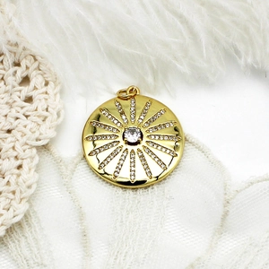 Macro shot of gold sunburst pendant with micro-pave cubic zirconia on white feather