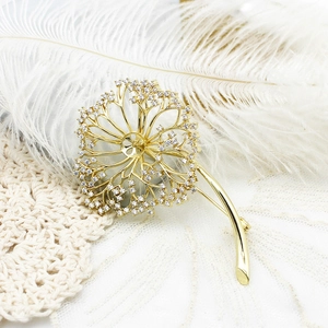 Elegant gold dandelion brooch with micro-set zircons displayed on lace and feathers