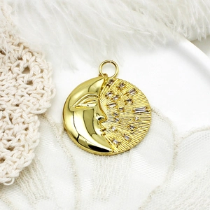 Macro detail of gold moon pendant with micro-paved zircons on white lace background