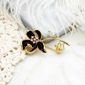Elegant camellia pearl brooch with black enamel and gold accents on a lace backdrop