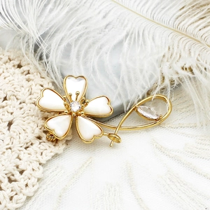 Broche fleur trèfle élégante avec pétales en nacre et accents dorés sur fond blanc