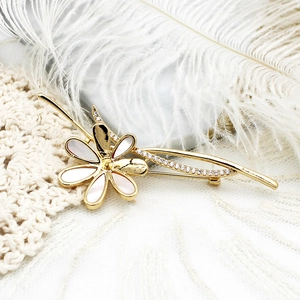 Macro detail of elegant golden camellia brooch with white mother of pearl and zircon stones