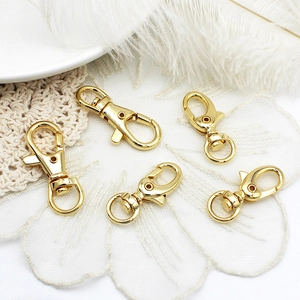 Close-up of five 18K gold plated lobster clasps for DIY jewelry on a white lace background