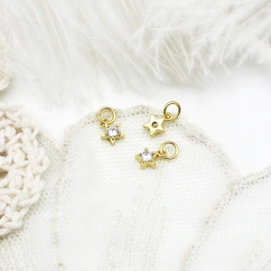 Macro detail of three 18K gold star pendants with zircons on white feather background