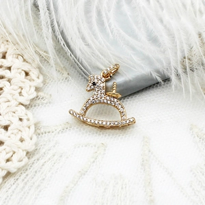 Detailed view of a gold-plated rocking horse pendant with micro-pave white zircons