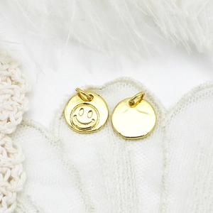Macro view of 18K gold-plated smiley face pendants on lace and feather background