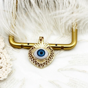 Close-up of gold 18K plated heart pendant with evil eye inlay and sunburst design