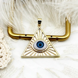 Detail of 18K gold-plated triangular Eye of Providence pendant on white lace and feather
