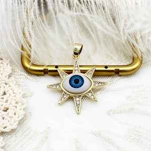 Detailed close-up of 18K gold-plated starburst pendant with Evil Eye and white zircons