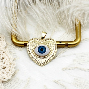 Detailed macro view of 18K gold heart pendant with evil eye motif and wing texture
