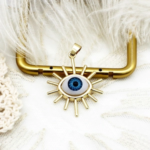 Detailed view of an 18K gold plated evil eye pendant on a U-shaped display stand