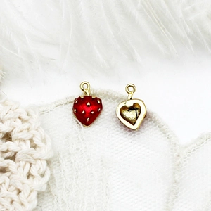 Macro detail of 18K gold plated strawberry charms with red enamel for DIY jewelry