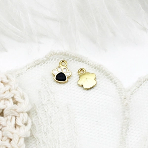 Macro view of gold-plated cat paw pendants with black and white enamel for DIY jewelry