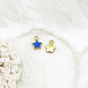 Macro shot of 18K gold plated blue star charms with smiling faces on lace background