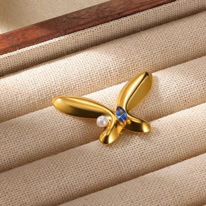 Gold-plated butterfly brooch with zircon blue gem and pearl on a jewelry tray