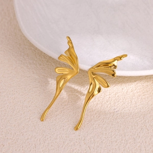 Polished gold butterfly stud earrings with textured fluid wings on elegant ceramic display