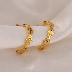 Goldene Hamsa-Hand-Ohrringe in C-Form mit Evil Eye-Detail auf elegantem weißem Seidenstoff