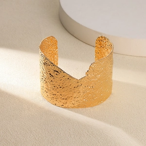 Détail d'un bracelet manchette large doré 18 carats avec texture martelée artistique