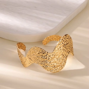 Detail of wide 18K gold plated cuff bracelet with unique hammered texture and wavy edges