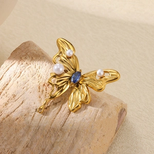 Vintage golden butterfly brooch with elegant white pearls and blue marquise gemstone