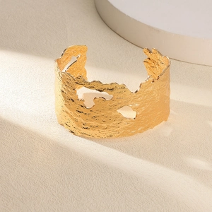 Détail macro du bracelet large plaqué or 18K avec texture lave et motifs ajourés
