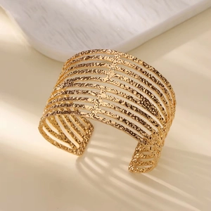 Detailed view of wide 18K gold plated cuff bangle with unique hammered texture and cut-out bars