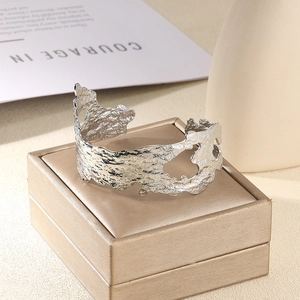 Détail macro du bracelet manchette argenté avec texture martelée et découpes ajourées