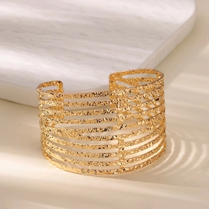 Detail view of gold wide open cuff bracelet featuring horizontal stripes and hammered texture
