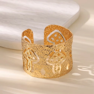 Detail of 18K gold plated wide cuff bracelet featuring hammered texture and mushroom cutouts