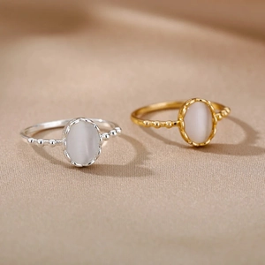 Detail of gold and silver beaded oval opal rings on elegant champagne silk fabric