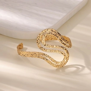 Macro shot of 18K gold plated wide cuff bracelet with S-curve textured surface