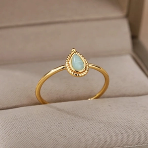 Detail of a pear-shaped pale green gemstone set in a vintage gold beaded ring band