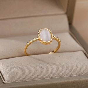 Close-up of gold-plated ring with white oval opal and vintage lace setting design
